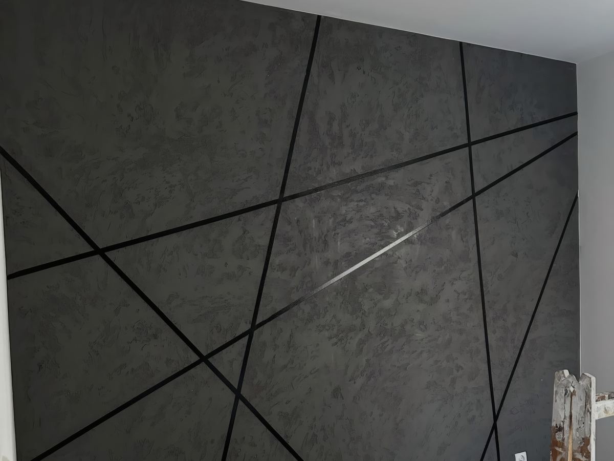 Ciemna ściana z betonu architektonicznego z czarnymi listwami w geometrycznym układzie